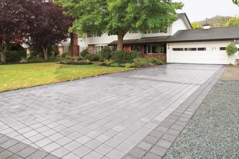 Paver driveway featuring a modern design, surrounded by landscaped lawn and trees, showcasing hardscape elements relevant to Authentic Homescapes' outdoor living services in Lancaster, PA.