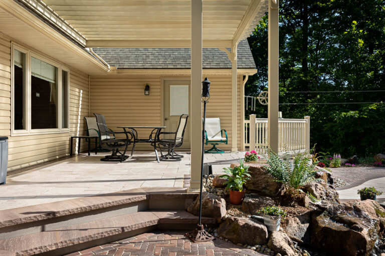 Landscape design by Authentic Homescapes showcasing an inviting outdoor living area with hardscape and a water feature.